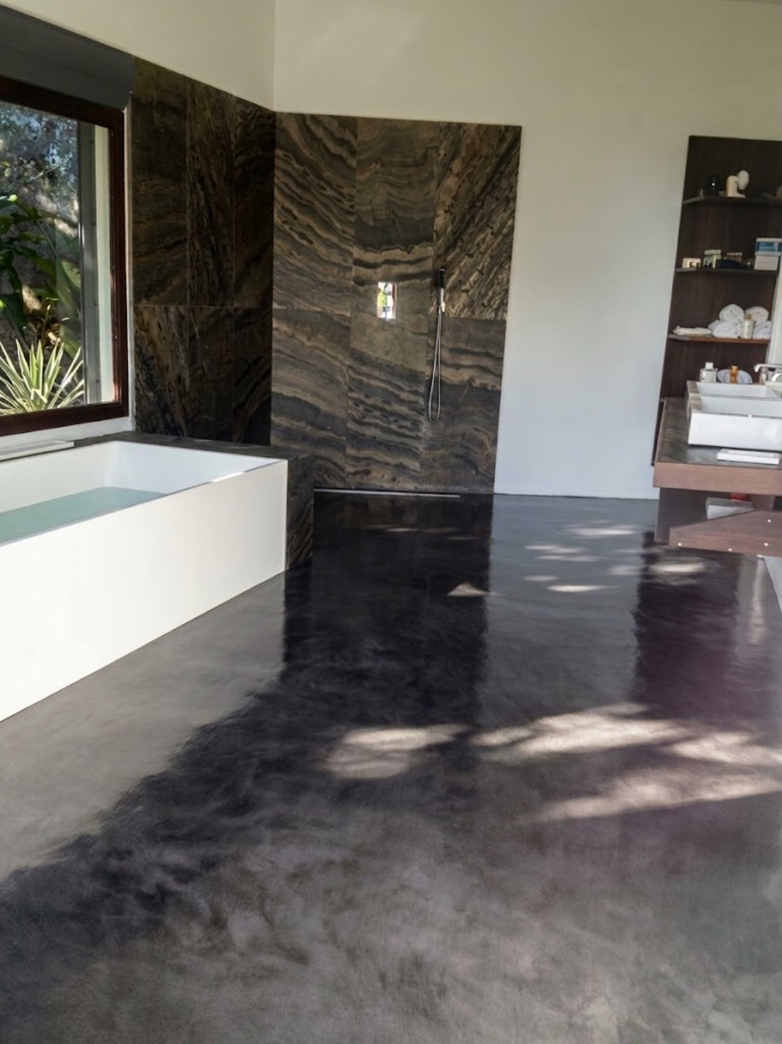 Salle de bain avec sol en béton minéral anthracite et mur en pierre naturelle
